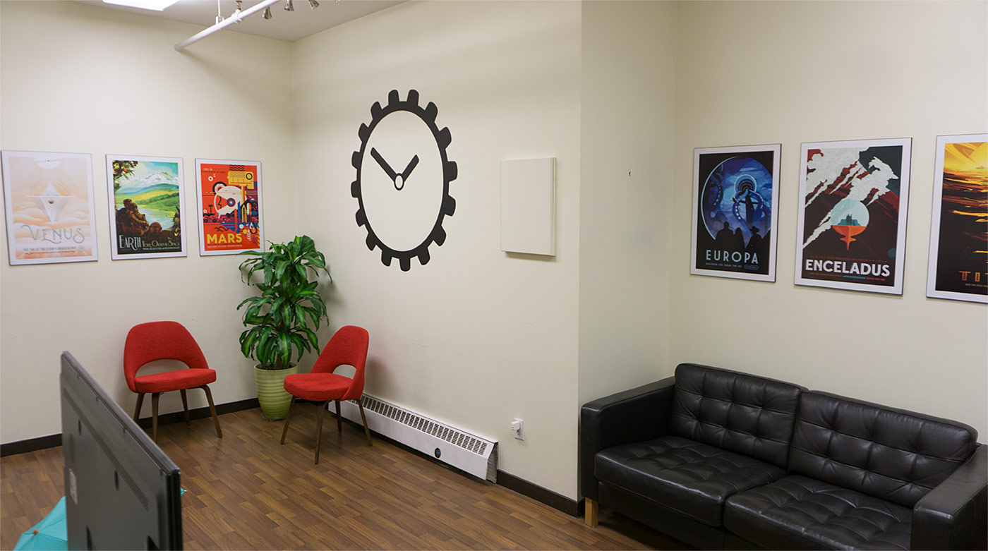 View of Steamclock's office entrance featuring the logo on the wall alonside bright artwork, stylish furniture, and a large plant